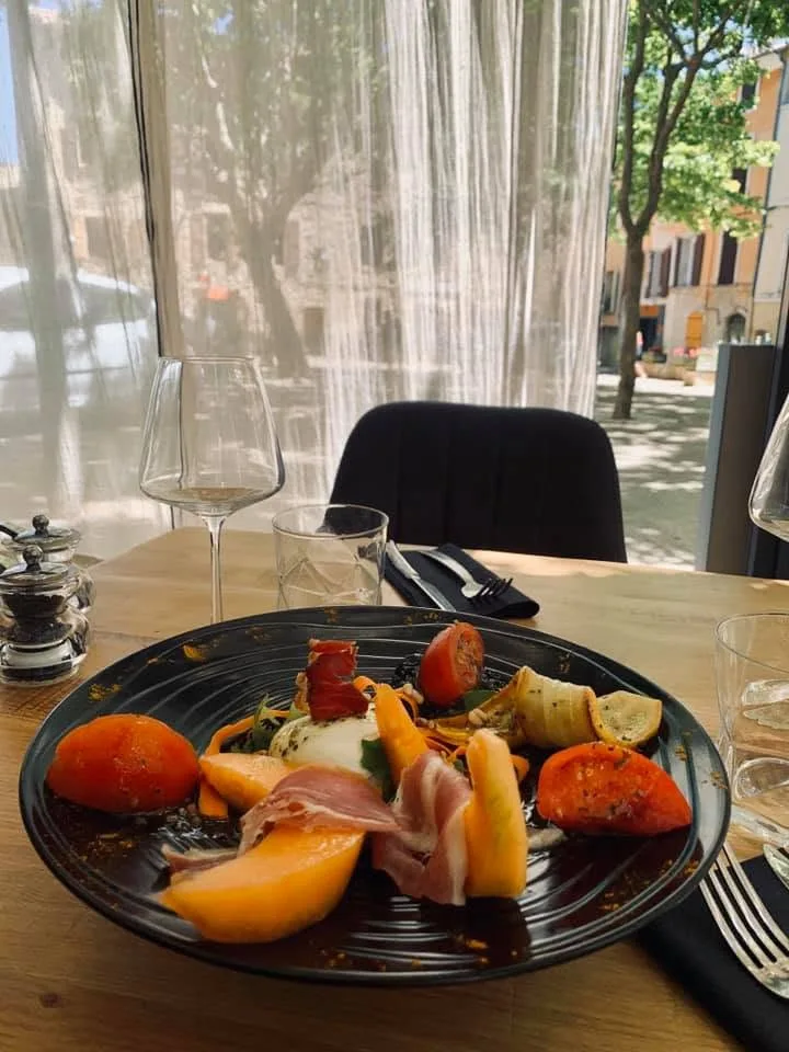 Table dressée devant la fenêtre du restaurant, vue sur la place